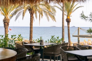 A seaside restaurant with outdoor seating, palm trees, and a view of the sea. - Pirates Beach Club - All Inclusive (Kemer)