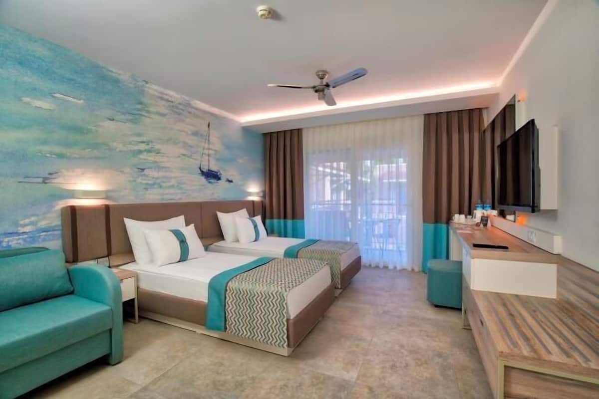 A hotel room with a bed, a desk, a TV, and a painting on the wall.