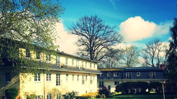 A large, two-story building with a well-maintained lawn and garden. - FerienResidenz MüritzPark (Röbel/Müritz)