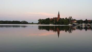 A calm lake with a church and boats in the background.