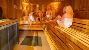 A sauna with wooden benches and a metal basin. - FerienResidenz MüritzPark (Röbel/Müritz)