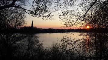 A sunset over a calm lake with a church spire silhouetted against the sky.