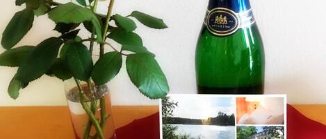 Et bord med en grøn flaske, to røde roser og et klart glas.