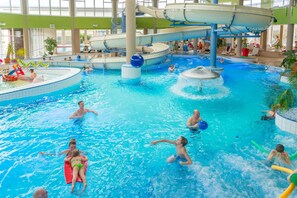 An indoor swimming pool with multiple slides and a central water feature. - FerienResidenz MüritzPark (Röbel/Müritz)