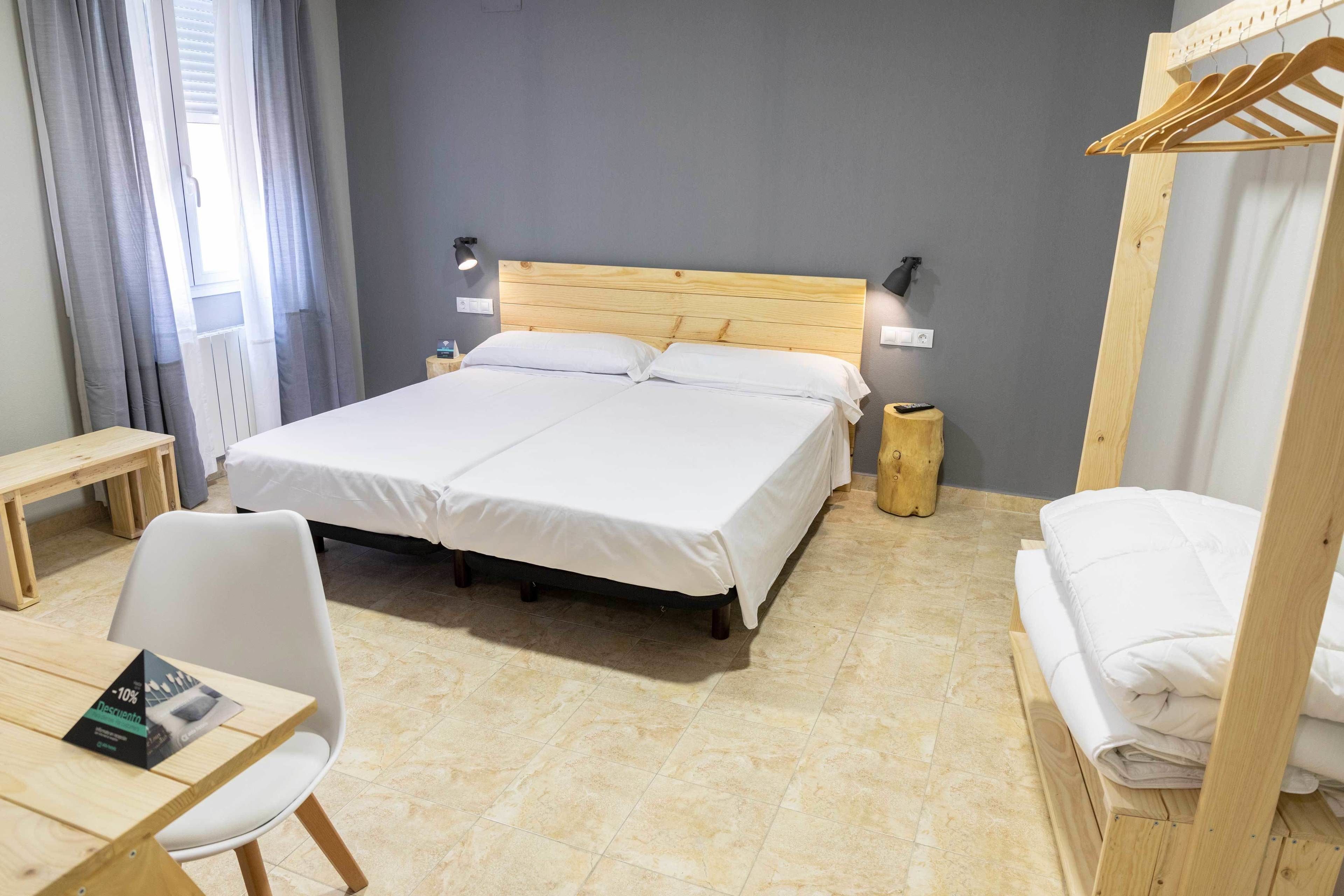 A neatly arranged hotel room with a large bed, bedside tables, a chair, and a wooden wardrobe.
