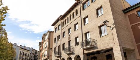 A multi-story building with a brick facade, multiple balconies, and a courtyard with benches.