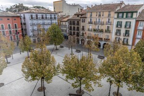 Uma praça com árvores e bancos, rodeada por edifícios altos com varandas e janelas.