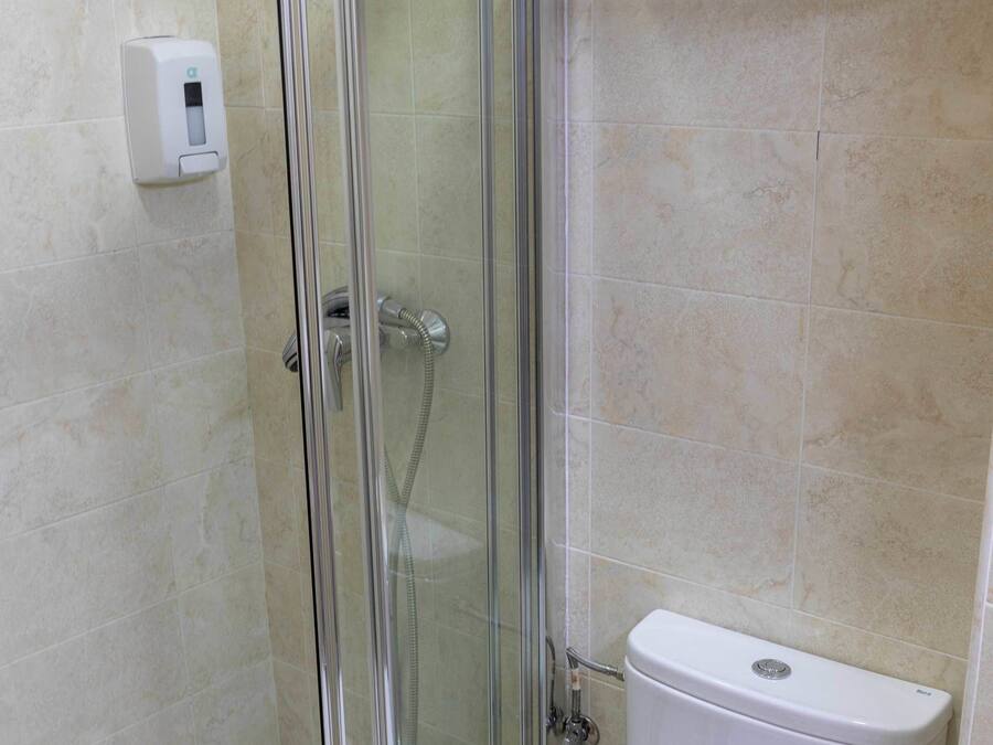 A bathroom with a glass-enclosed shower, a white toilet, and a towel rack above the toilet.