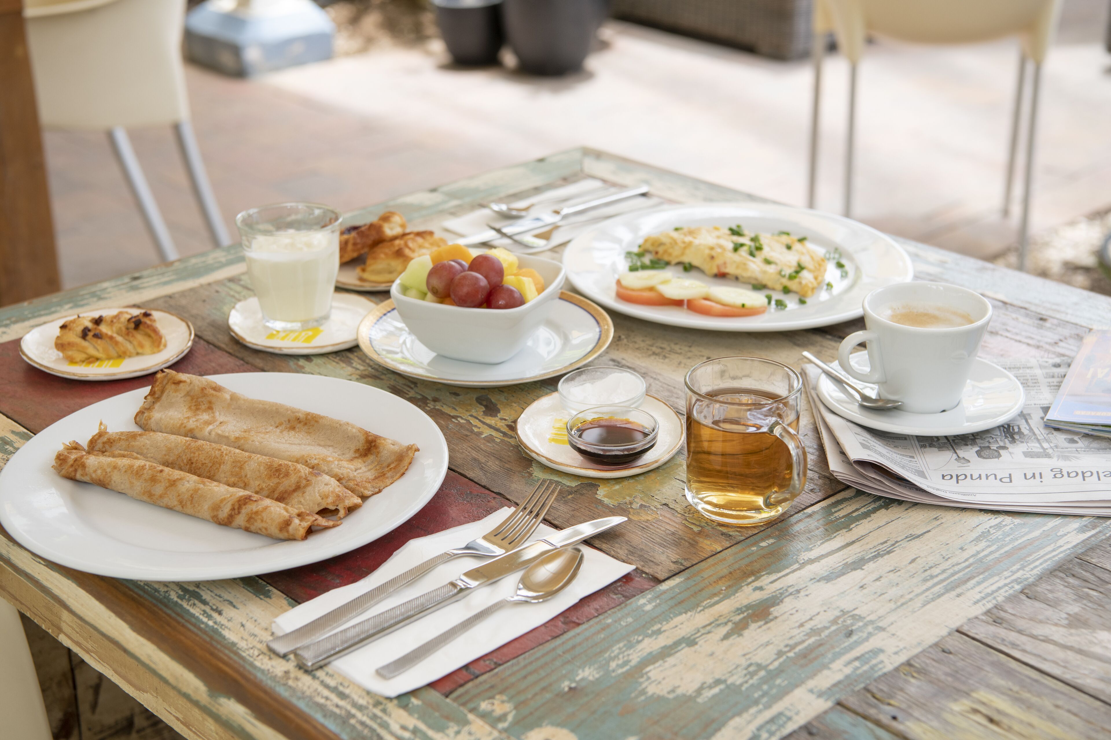 Una mesa dispuesta con alimentos para el desayuno, como cruasanes, fruta, huevos y café.