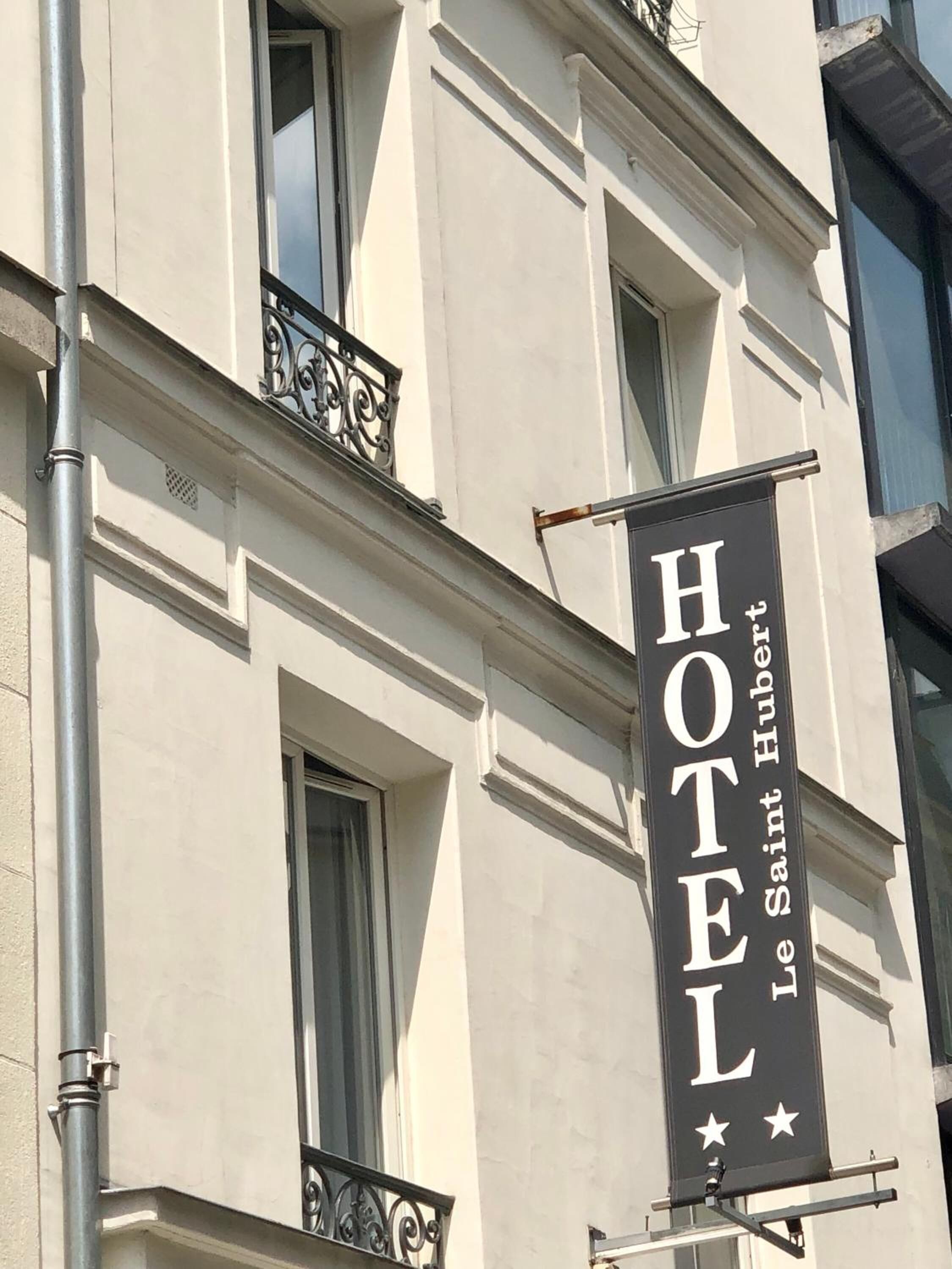 Un letrero de hotel con los nombres 'HOTEL' y 'Le Saint Hubert' escritos.