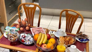 Una mesa de desayuno con diversas opciones de comida, como frutas, pastelería y bebidas.