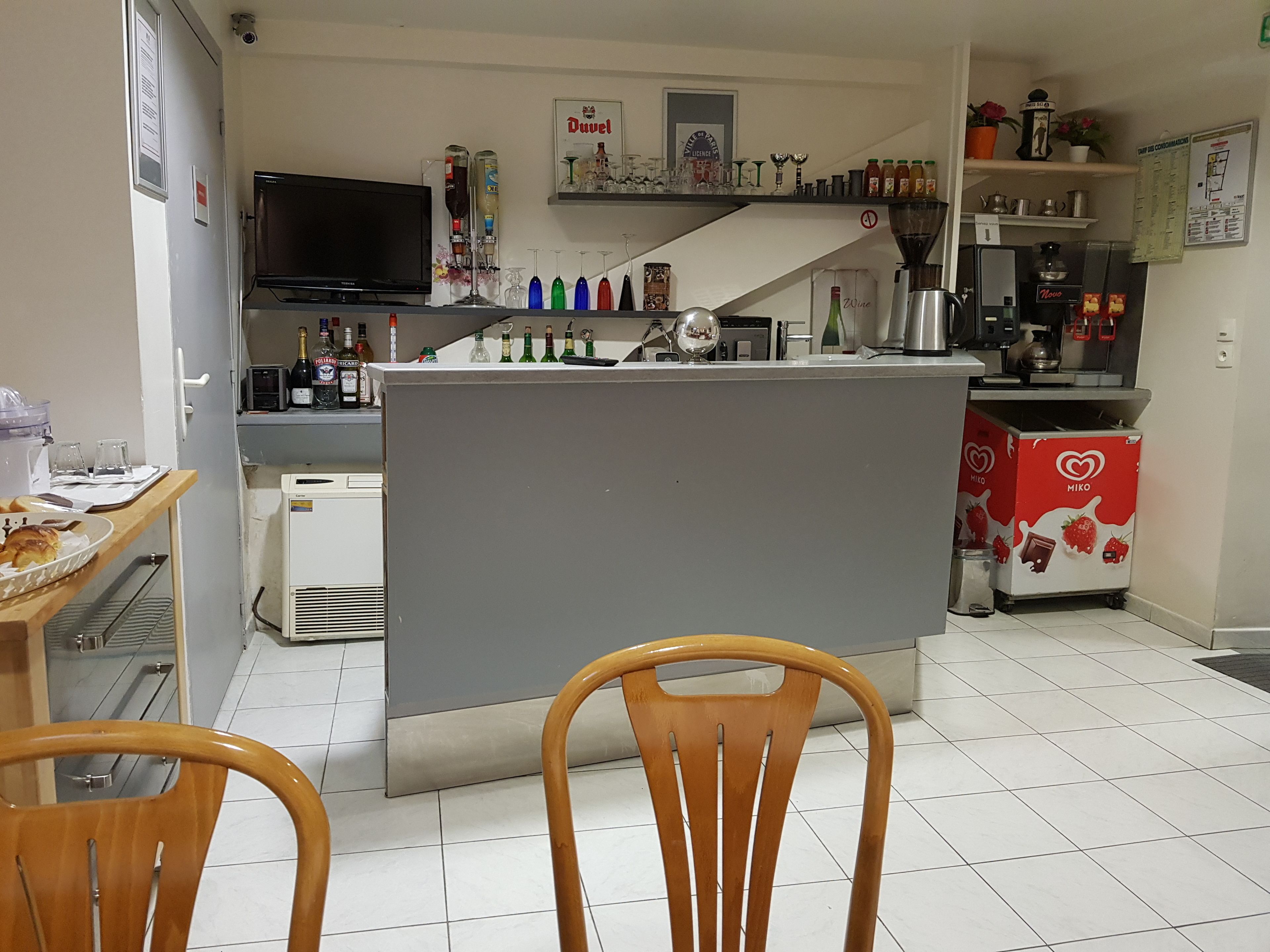Una cocina compacta con una isla central, un televisor de pantalla plana montado en la pared y diversos electrodomésticos.
