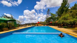 A swimming pool with a tiled edge, surrounded by trees and outdoor seating areas. - Leleshwa Getaway (Nairobi)