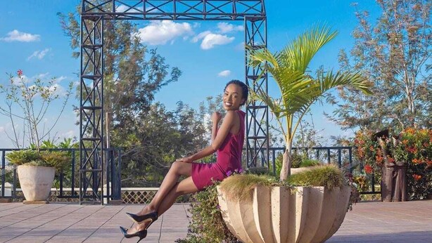 A woman sitting on a bench in an outdoor area with a metal arch structure, surrounded by potted plants and trees. - Leleshwa Getaway (Nairobi)
