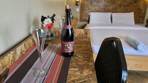A hotel room with a bed, a bedside table with a bottle of wine, glasses, and a decorative item. - Leleshwa Getaway (Nairobi)