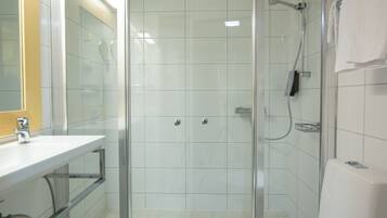 Un baño moderno con ducha de vidrio, lavamanos blanco y espejo.