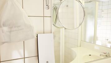 A bathroom with a white sink, a mirror, and a hair dryer bag hanging on the wall.