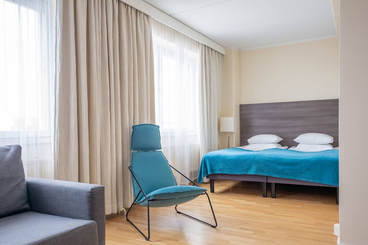 A hotel room with a bed, a chair, and a sofa.