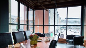 Ein Konferenzraum mit langem Tisch, schwarzen Stühlen und einem großen Fenster mit Blick auf die Stadt.