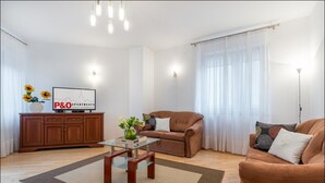 A modern living room with a brown sofa, a glass coffee table, and a TV on a wooden cabinet. - P&O Apartments Grodkowska (Warsaw)