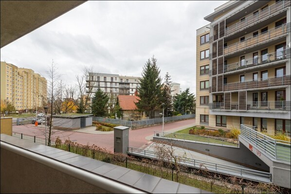 A residential building with multiple balconies, a courtyard with trees, and a parking area.