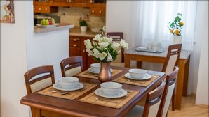 A dining table set with white plates, bowls, and a vase of white flowers. - P&O Apartments Grodkowska (Warsaw)