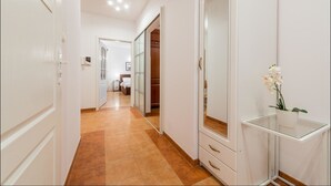 A hallway with a white wardrobe, a mirror, and a small table with a potted plant. - P&O Apartments Grodkowska (Warsaw)