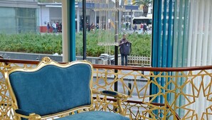 A luxurious seating area with a blue upholstered chair and a gold table set with tea and pastries. - Hotel Kralice (Istanbul)