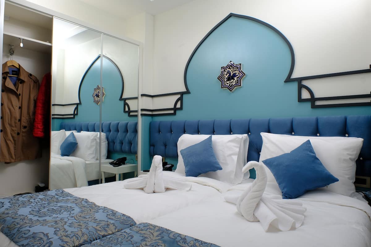 A hotel room with a large bed, a wardrobe, and a mirror.