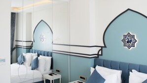 A modern bedroom with a large bed, a nightstand, a mirror, and decorative wall art. - Hotel Kralice (Istanbul)