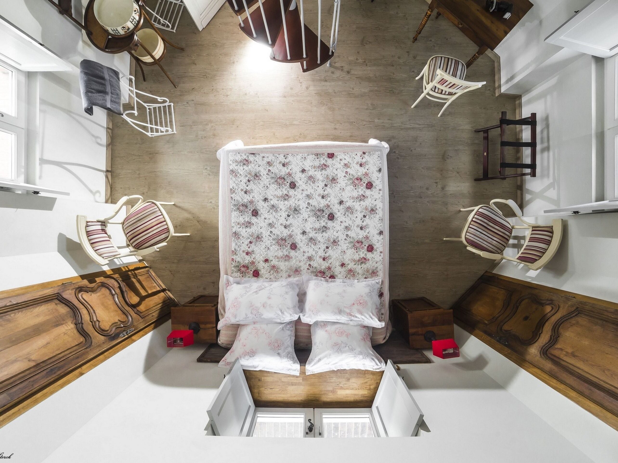 Un dormitorio con cama, dos sillones, un aparador de madera y una ventana.