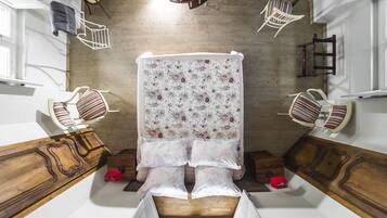 Un dormitorio con cama, dos sillones, un aparador de madera y una ventana.