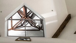 Un interior moderno con tragaluces, vigas de madera y un cuadro enmarcado en la pared.
