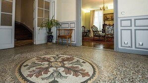 Un vestíbulo amplio con suelo estampado, un banco de madera y una planta en maceta.