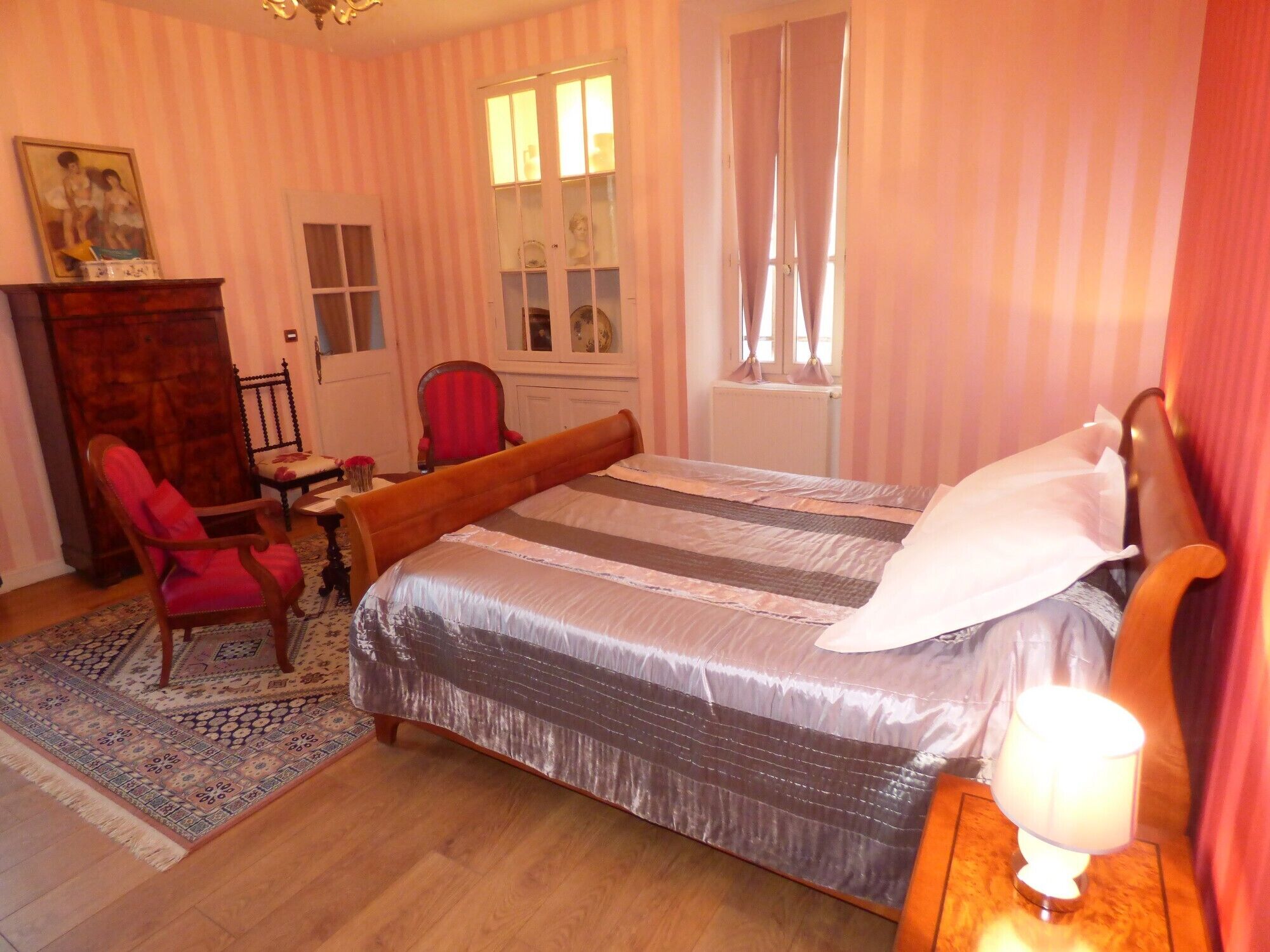 A bedroom with a bed, a chair, a desk, a dresser, and a window with curtains.