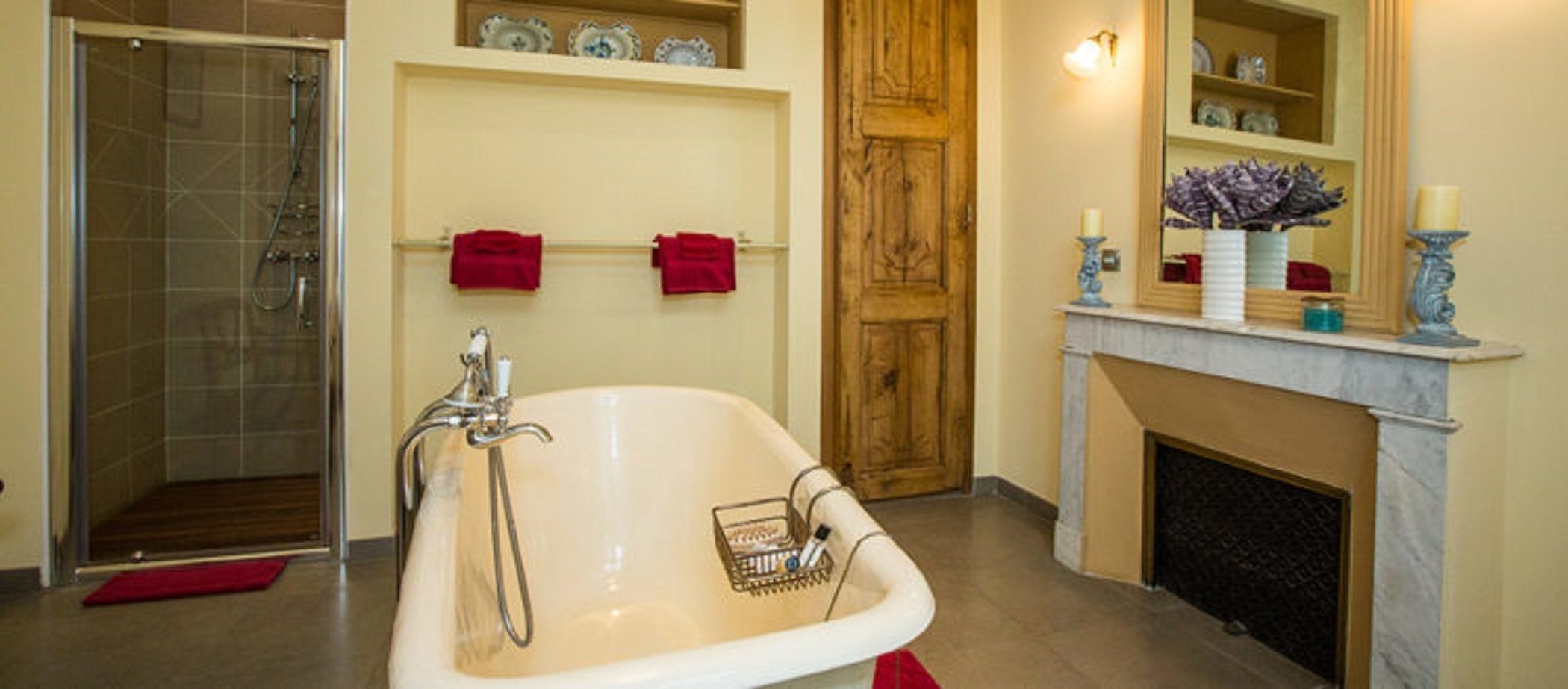 A bathroom with a freestanding bathtub, a shower, and a fireplace.