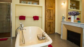 A bathroom with a freestanding bathtub, a shower, and a fireplace.