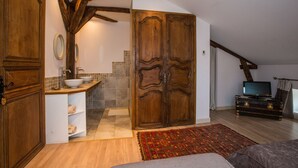 Una habitación acogedora con un armario de madera, un lavabo y un televisor.