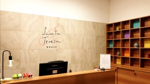 A reception desk with a YASHI laptop, a signboard, and a wooden shelf with colorful items. - Santa Teresa House (Verona)