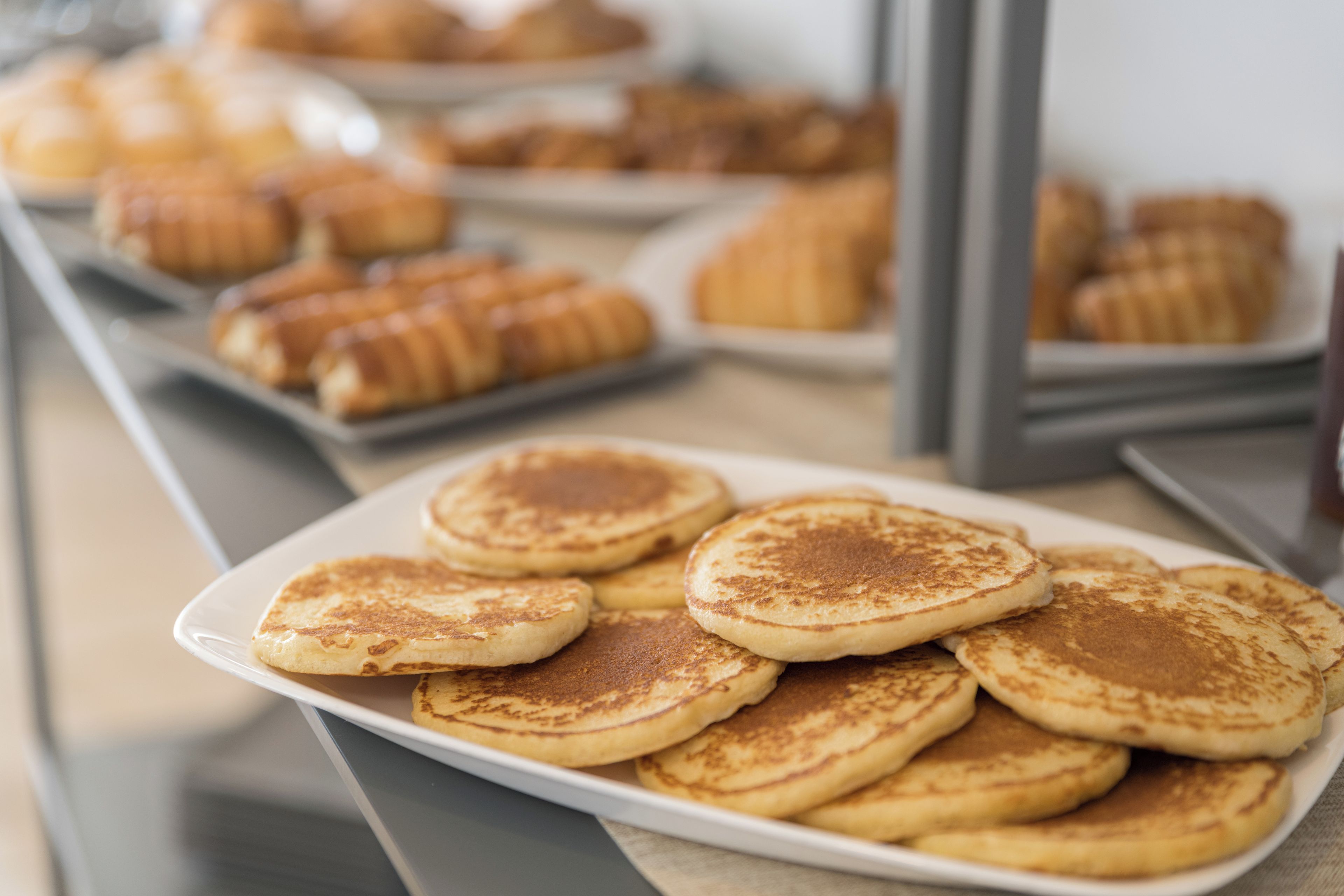 A plate of pancakes with a few pastries in the background.