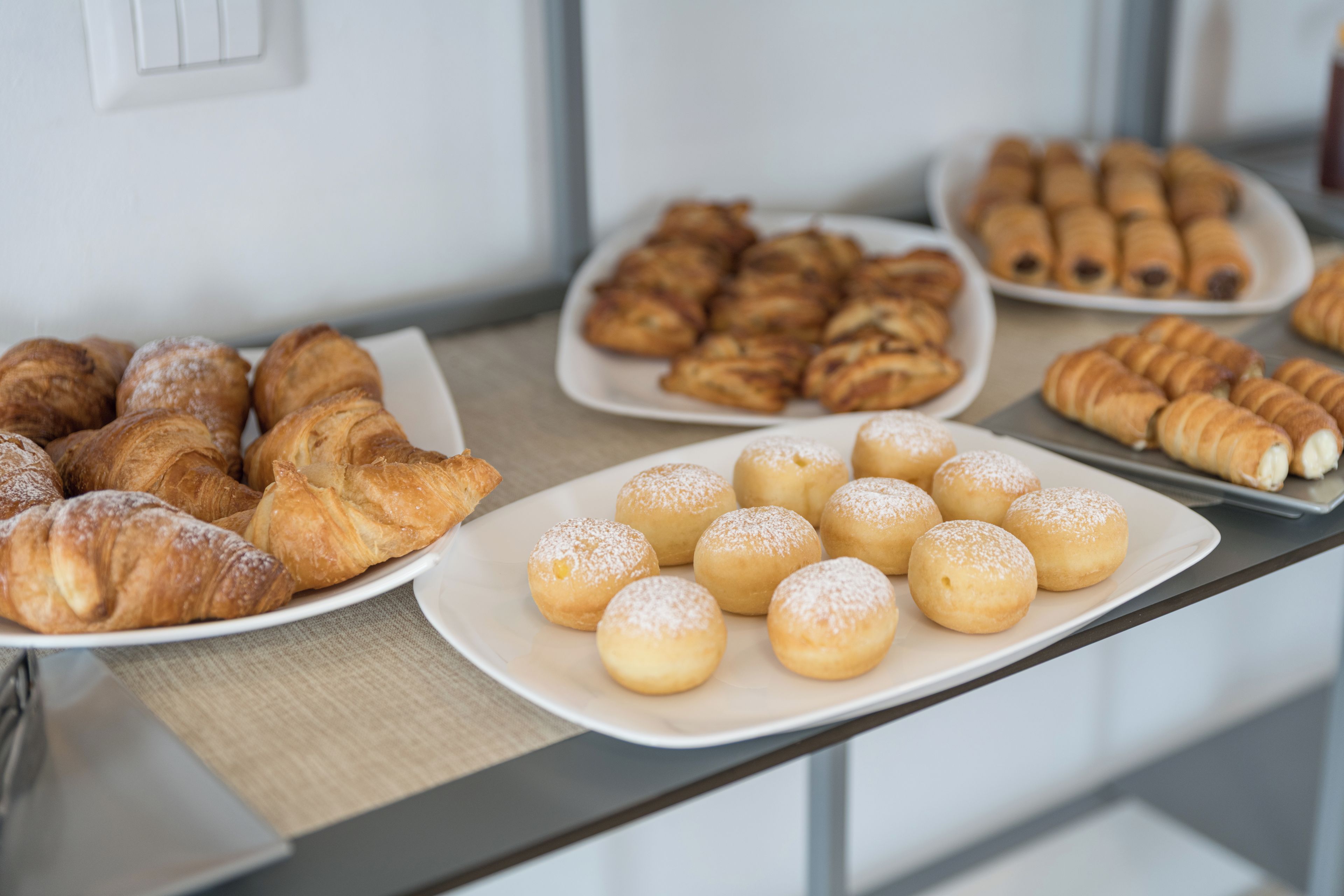 Ein Buffet mit verschiedenen Backwaren, darunter Croissants und Donuts.
