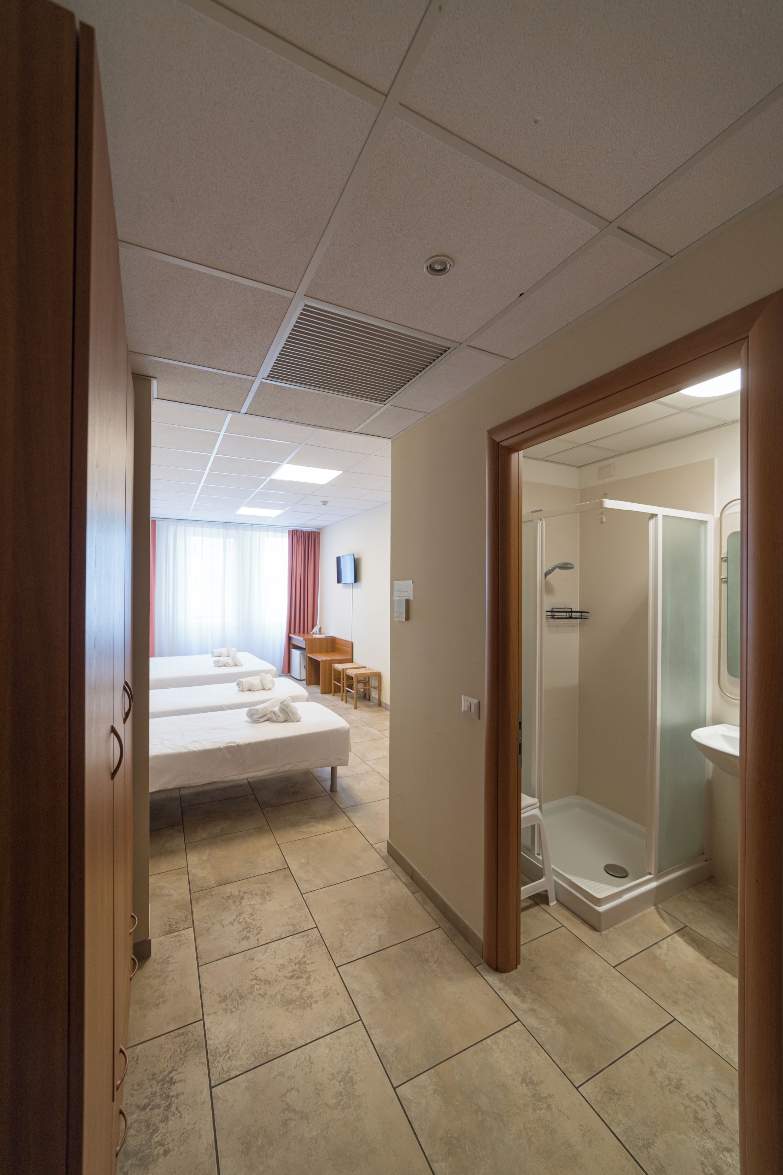 Une chambre d’hôtel avec deux lits, un bureau, une douche et une salle de bain.