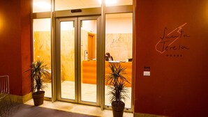 A hotel entrance with a reception desk, a sign reading "Sofia Teresa HOUSE", and two potted plants. - Santa Teresa House (Verona)