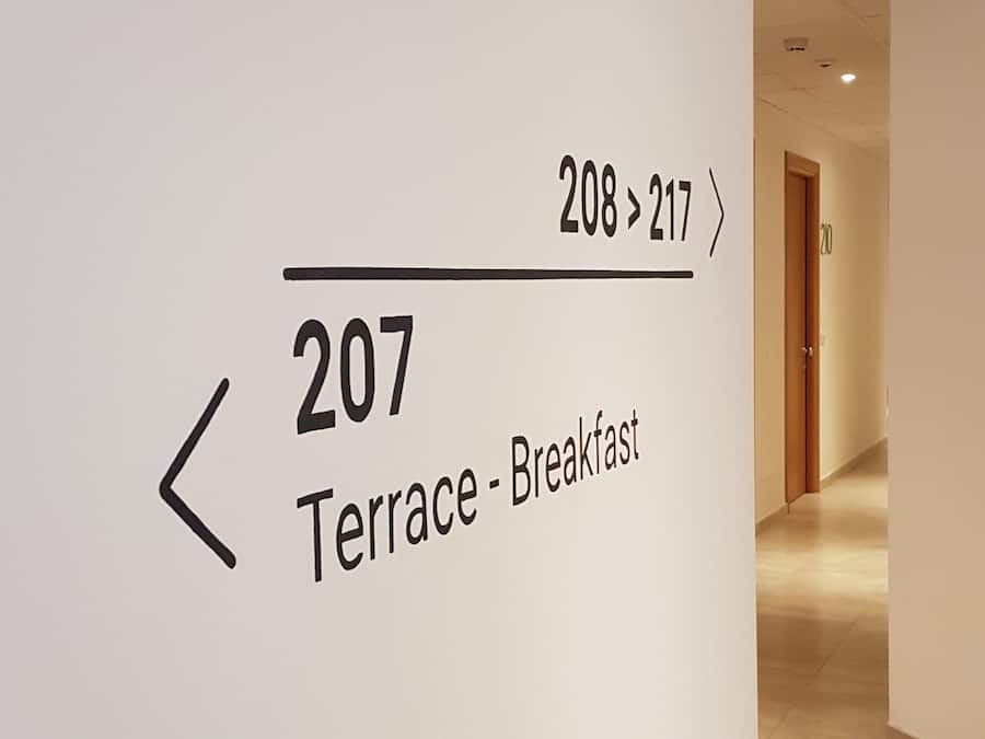 A hallway with a sign indicating the direction to the terrace and breakfast area.