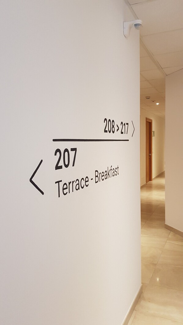 A hallway with a sign indicating the direction to the terrace and breakfast area. - Santa Teresa House (Verona)