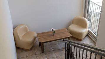 Una habitación pequeña con una mesa de madera, dos sillas, un cuadro en la pared y vistas por la ventana.
