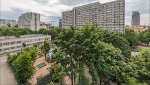 Un edificio residencial alto con varios balcones, rodeado de vegetación y un parque infantil.
