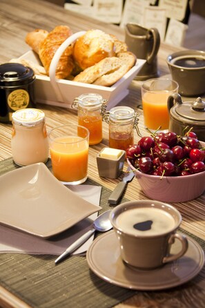 A breakfast setting with croissants, a bowl of cherries, a cup of coffee, and various breakfast items on a table. - L'Esprit des Chartrons (Bordeaux)