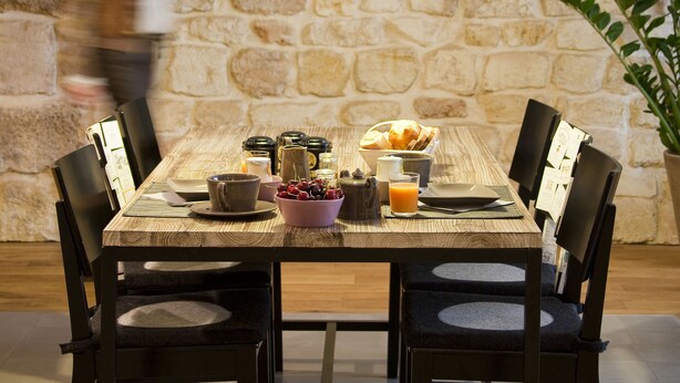 Une table à manger avec des chaises, un mur en pierre et un luminaire suspendu.