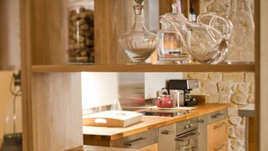 Une cuisine dotée de meubles en bois, d’une machine à café et de divers ustensiles de cuisine rangés sur les étagères.